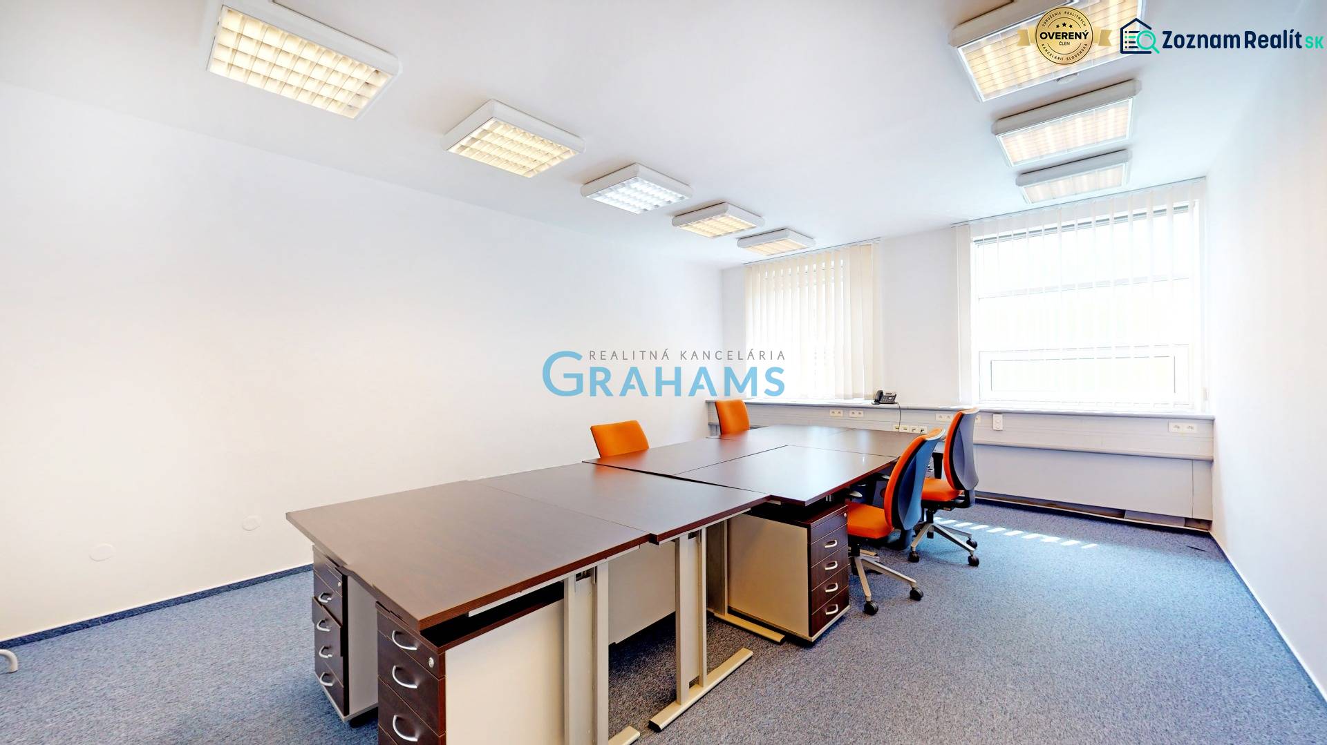 Ein Büro mit orangefarbenen Stühlen und einem Eckfenster, der Raum ist mit Vorhängen ausgestattet.