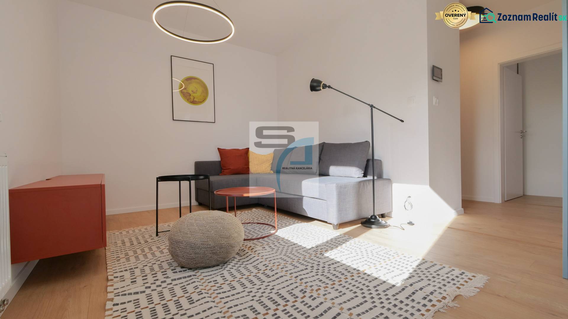 Wohnzimmer in einer 2-Zimmer-Wohnung mit Holzboden, grauem Sofa und moderner Beleuchtung.