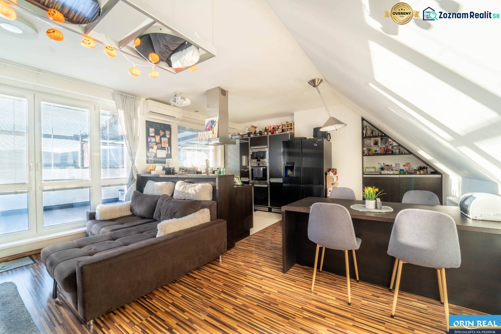 Wohnzimmer mit Küche in einer 2-Zimmer-Wohnung mit Holzboden und bequemer Couch.