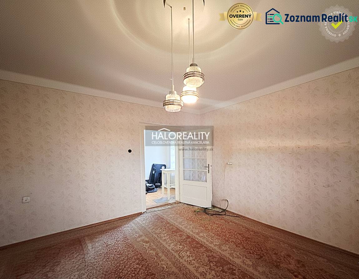 Ein Zimmer in einem Einfamilienhaus mit Teppichboden und Hängelampe.