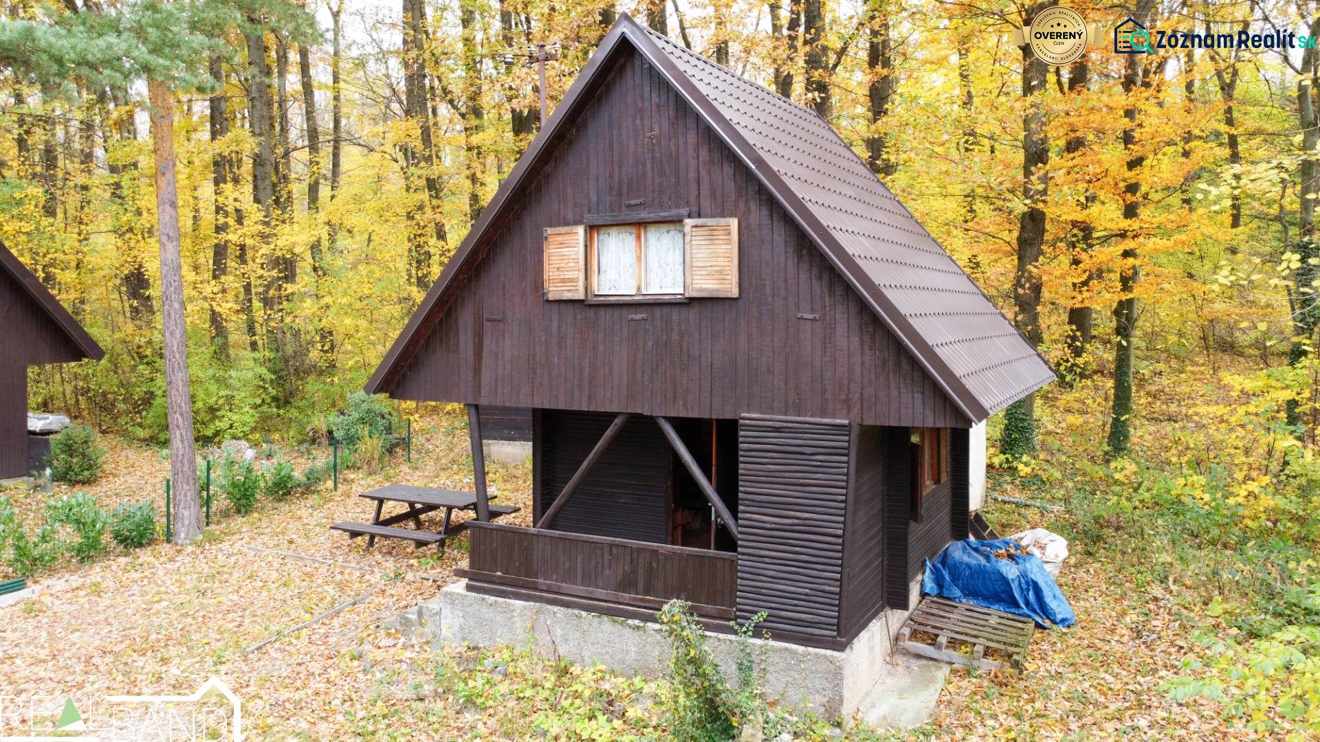 Eine Hütte in Prievaly, umgeben von einem herbstlichen Wald, mit Holzeinrichtung und Holzläden.
