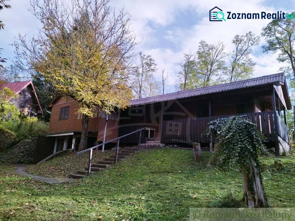 Ein Ferienhaus in Dudince, umgeben von Natur, mit Terrasse und Bäumen im Garten.