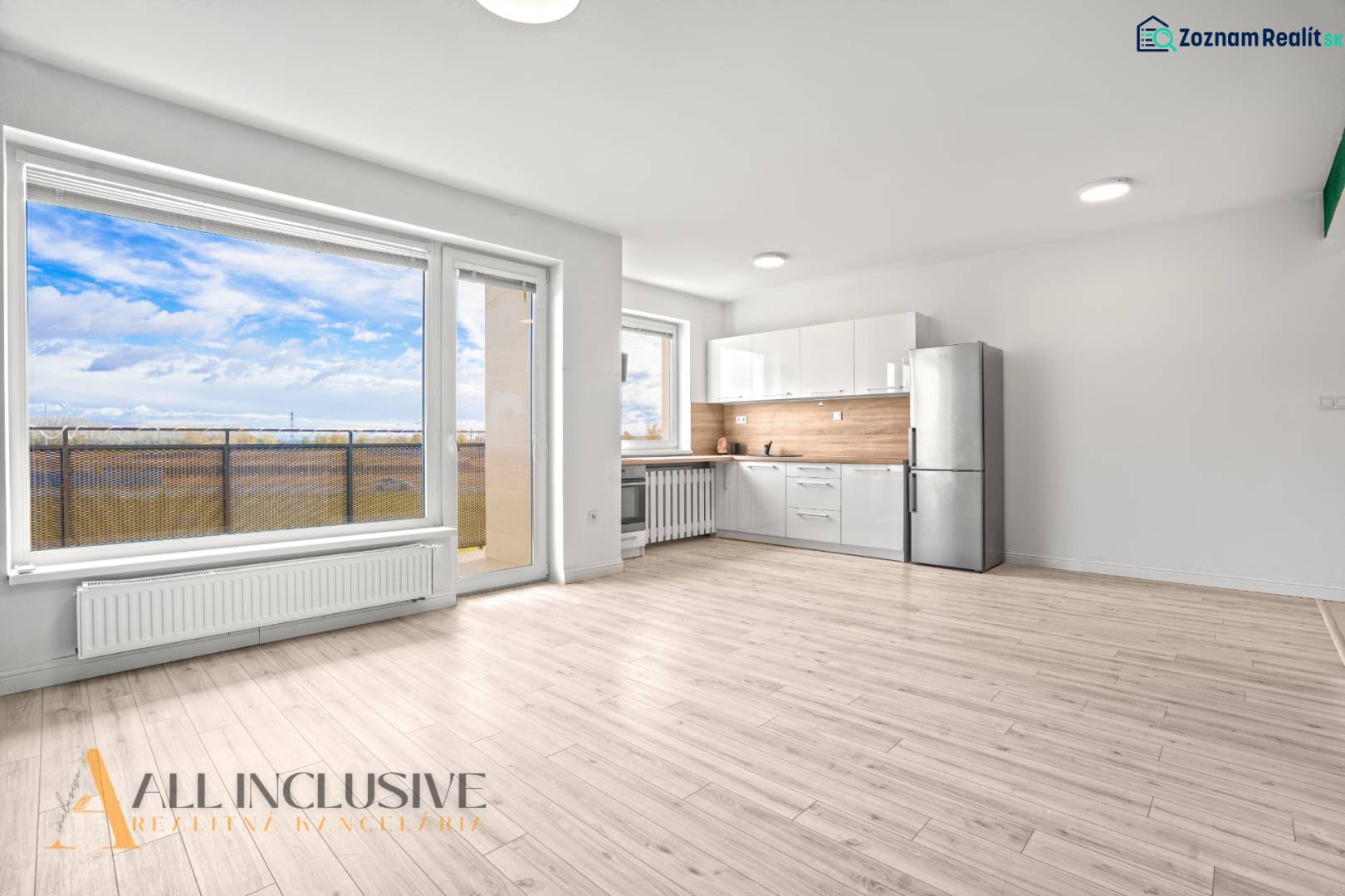 Helles Interieur einer 2-Zimmer-Wohnung mit Küche, verglaster Wand und Boden in Holzoptik.