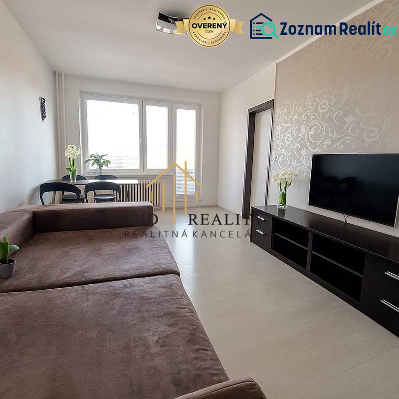 Wohnzimmer in einer 3-Zimmer-Wohnung mit großem Sofa, Fernseher und Boden in Holzoptik.