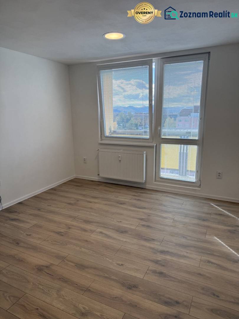 Einzimmerwohnung mit Holzboden und großem Fenster, das einen Ausblick auf die Umgebung bietet.