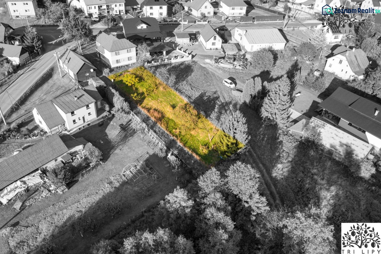 Baugrundstück in Turzovka, umgeben von Häusern, mit Grasbewuchs und Bäumen.