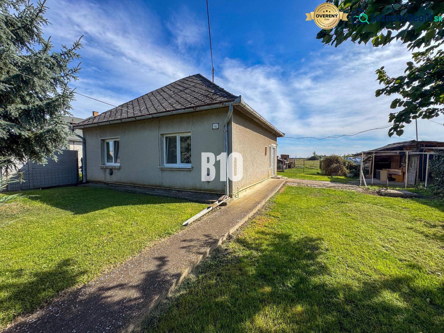 Ein Einfamilienhaus in Ondrejovce mit einem grasbewachsenen Hof unter blauem Himmel.