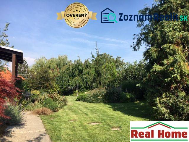 Ein Garten bei einem Einfamilienhaus in Čierna Voda mit reicher Bepflanzung und gepflegtem Rasen.