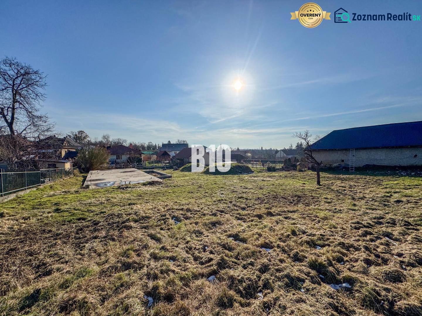 Ein Grundstück mit Betonfundament bereit zum Wohnen, sonniges Wetter und umliegende Landschaft.