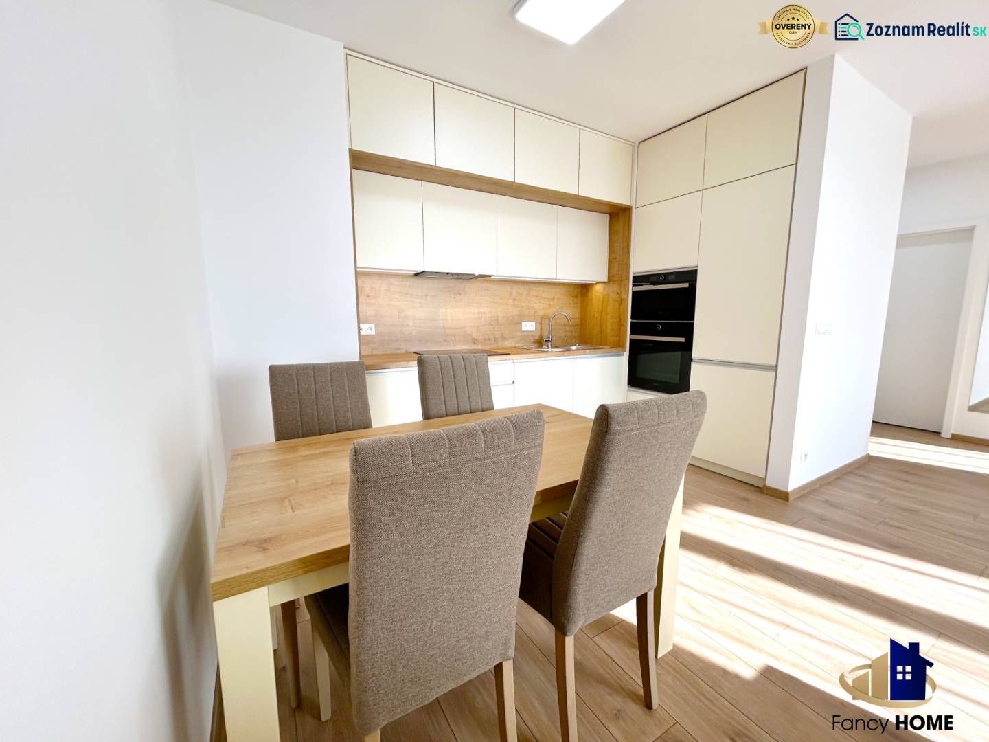 Küche in einer 2-Zimmer-Wohnung mit Esstisch und Stühlen, Boden mit Holzdekor.