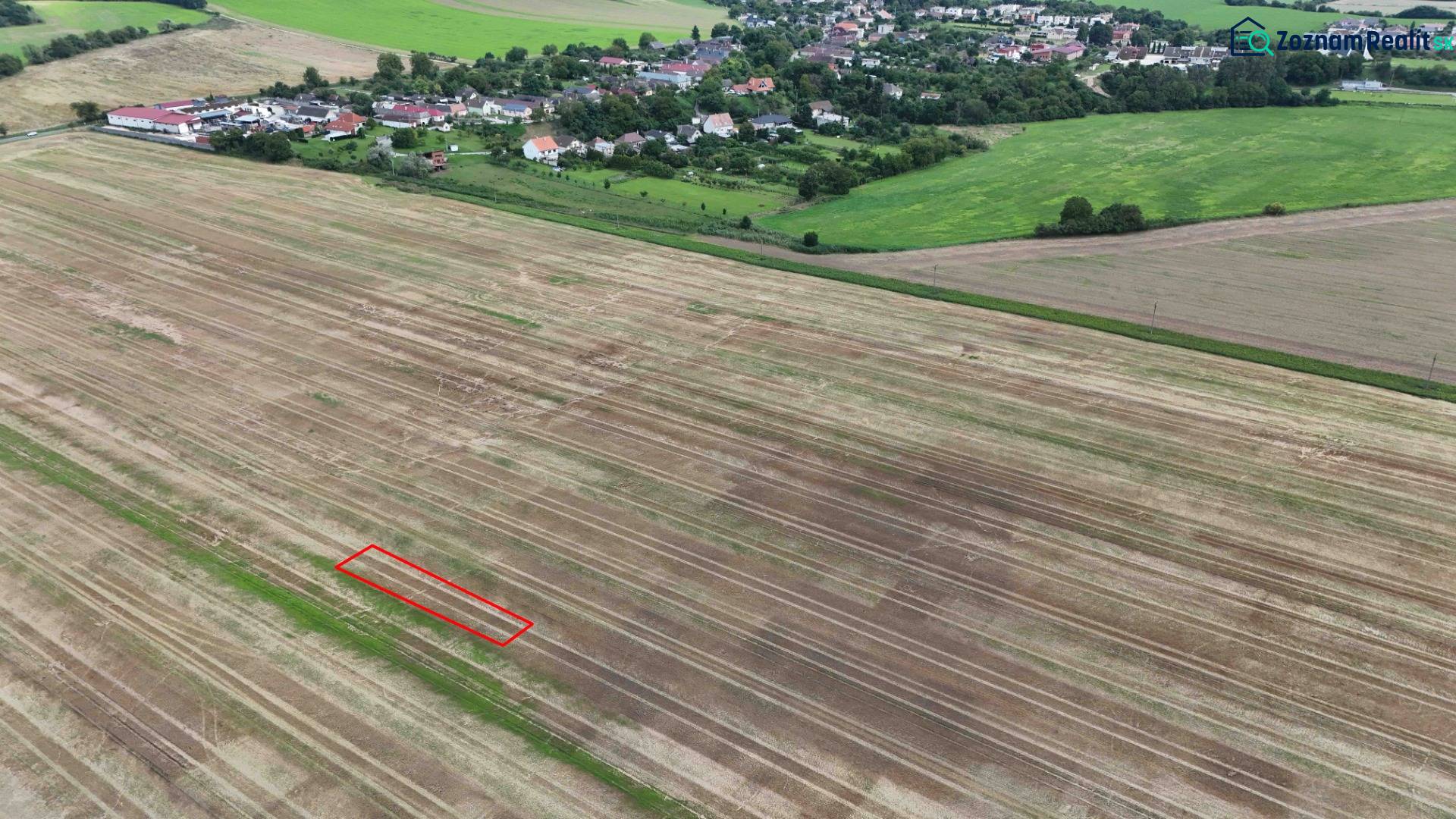 Landwirtschaftliche und forstwirtschaftliche Flächen bei Nová Ves nad Váhom mit einem Dorf im Hintergrund.
