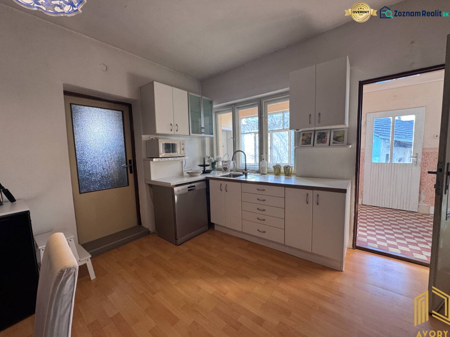 Küche mit weißer Küchenzeile und Boden in Holzoptik in einem Einfamilienhaus.