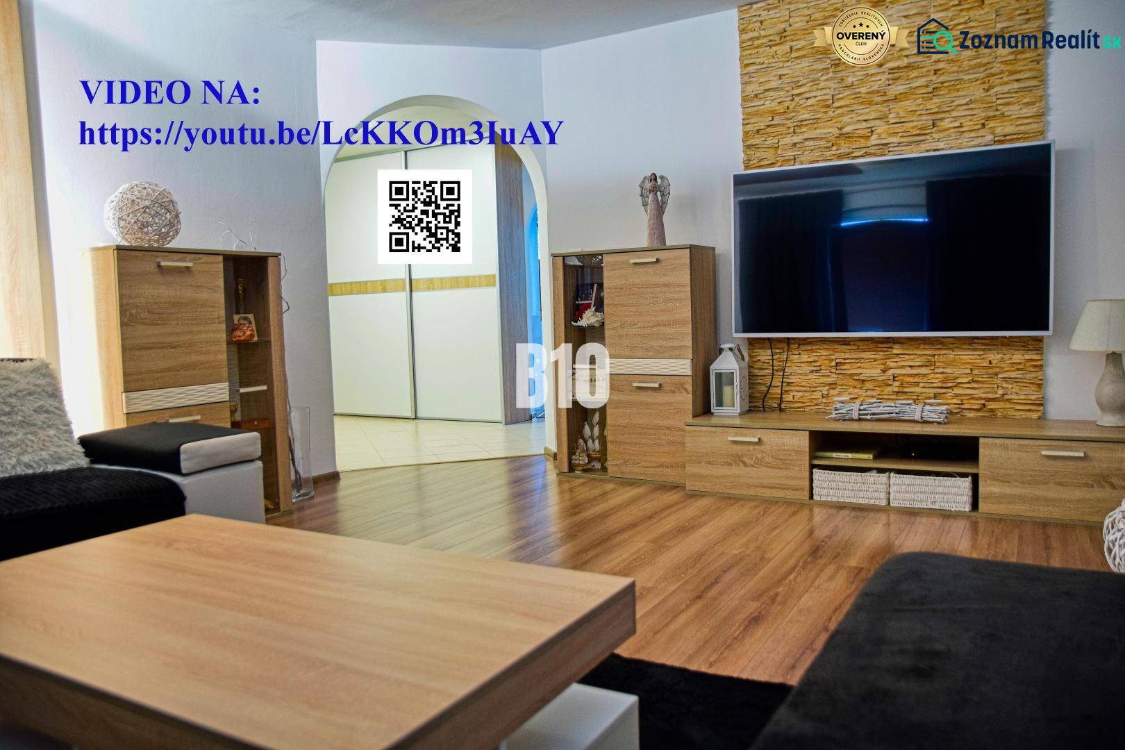 Wohnzimmer in einem Einfamilienhaus mit Fernseher, Holzmöbeln und Boden mit Holzdekor.