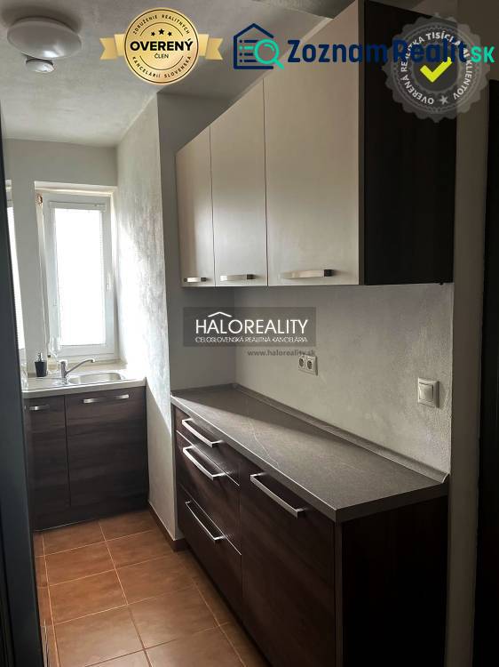 Küche in einer 3-Zimmer-Wohnung mit dunklen Schränken und einem Fenster.