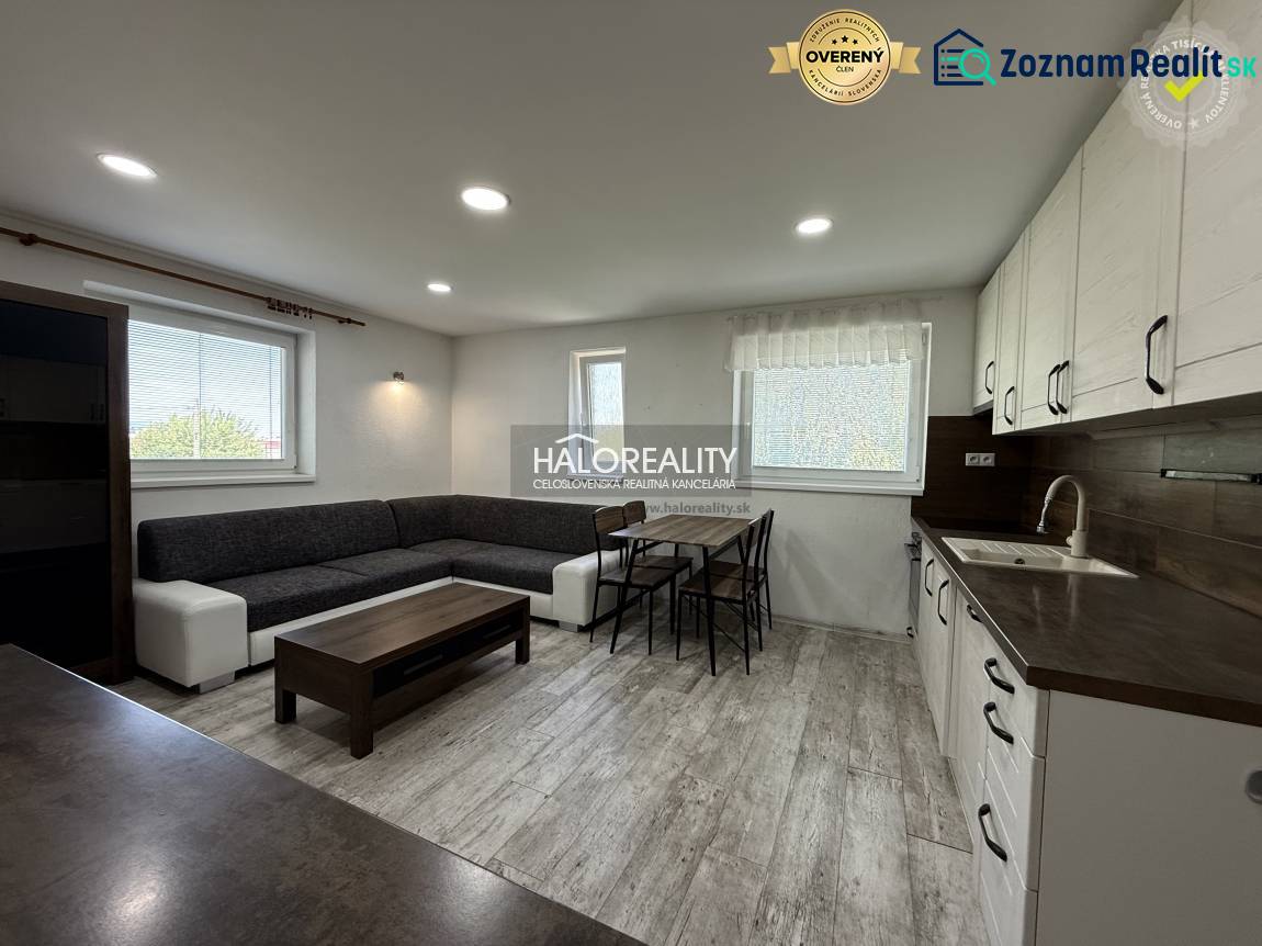 Wohnzimmer mit Küche, heller Boden, graues Sofa, Esstisch in einer 3-Zimmer-Wohnung.