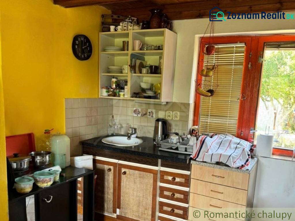 Küche in einer Hütte mit Holzdecke und gelber Wand, ausgestattet mit grundlegenden Geschirr.