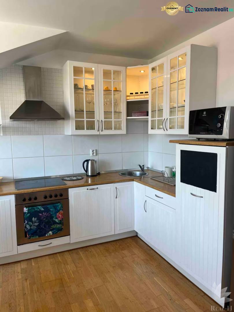 Küche in einer 3-Zimmer-Wohnung mit Holzboden, weißen Schränken und Stauraum.