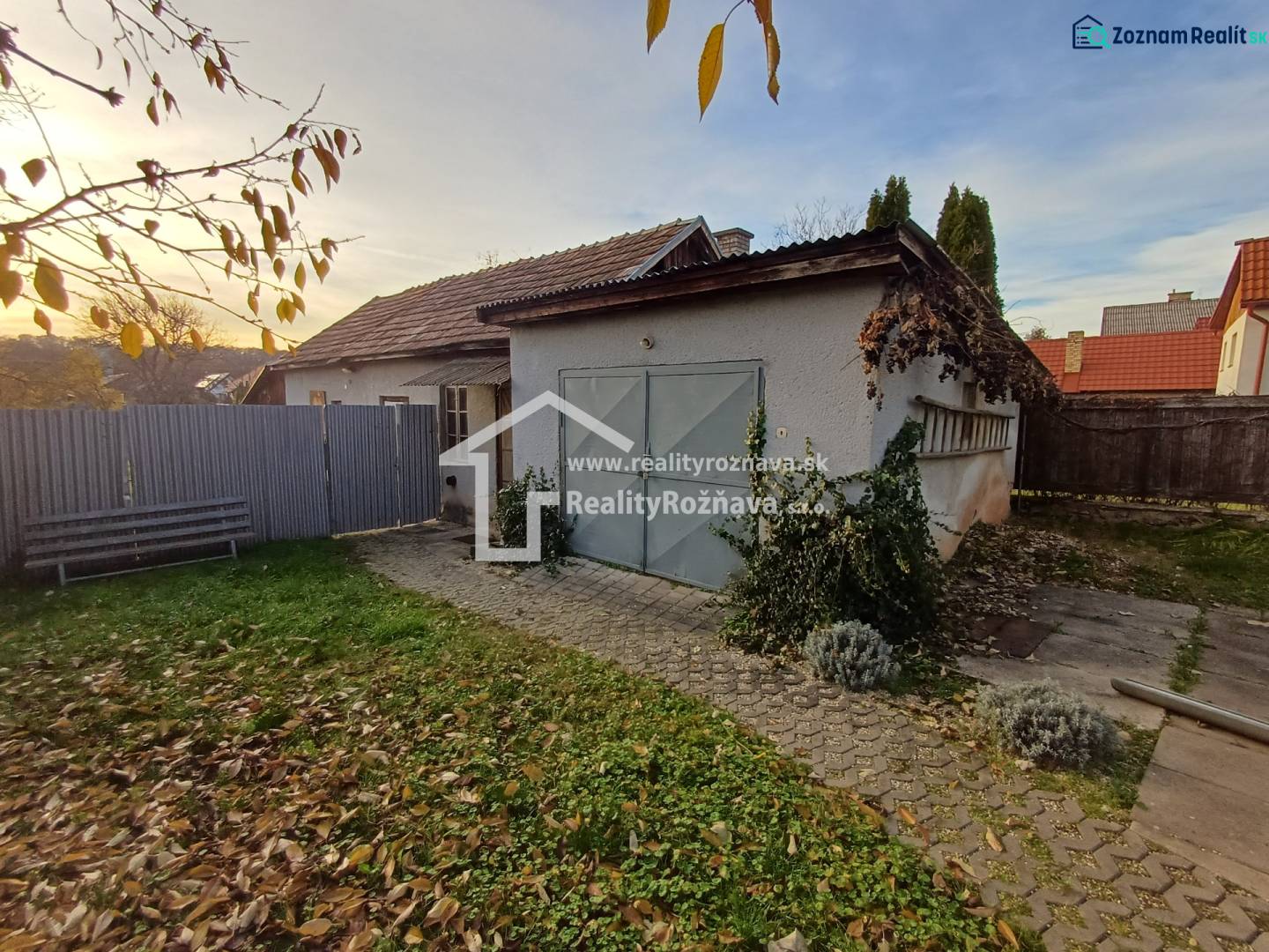 Ein Einfamilienhaus in Dlhá Ves mit einem Hof, einer Rasenfläche und einer Garage, umgeben von einem Zaun.