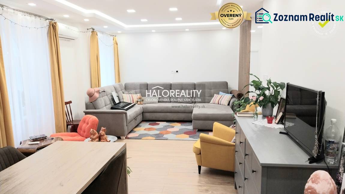 Wohnzimmer in einer 3-Zimmer-Wohnung mit Holzboden, grauem Sofa und gelbem Sessel.