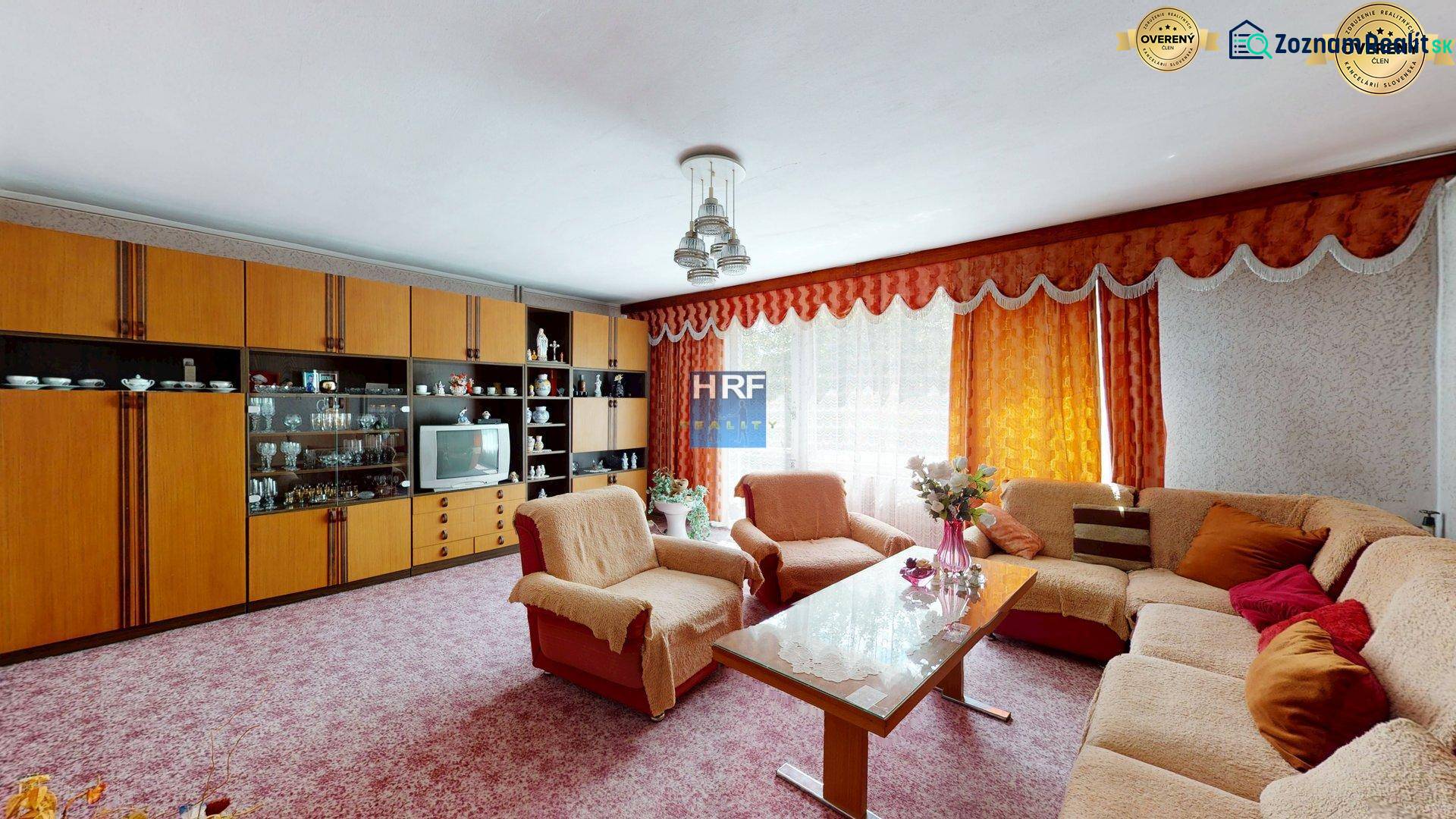 Wohnzimmer in einem Einfamilienhaus mit Sitzgarnitur, Wohnwand und Blumen.