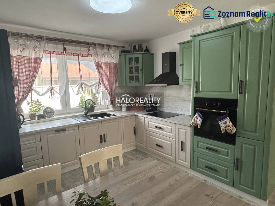 Küche in einem Einfamilienhaus mit Holzmöbeln und Vorhängen.