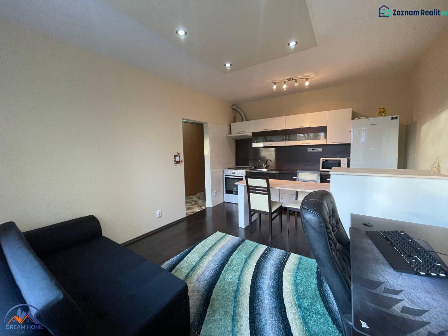 Innenraum einer 1-Zimmer-Wohnung mit Kochnische und Holzboden.