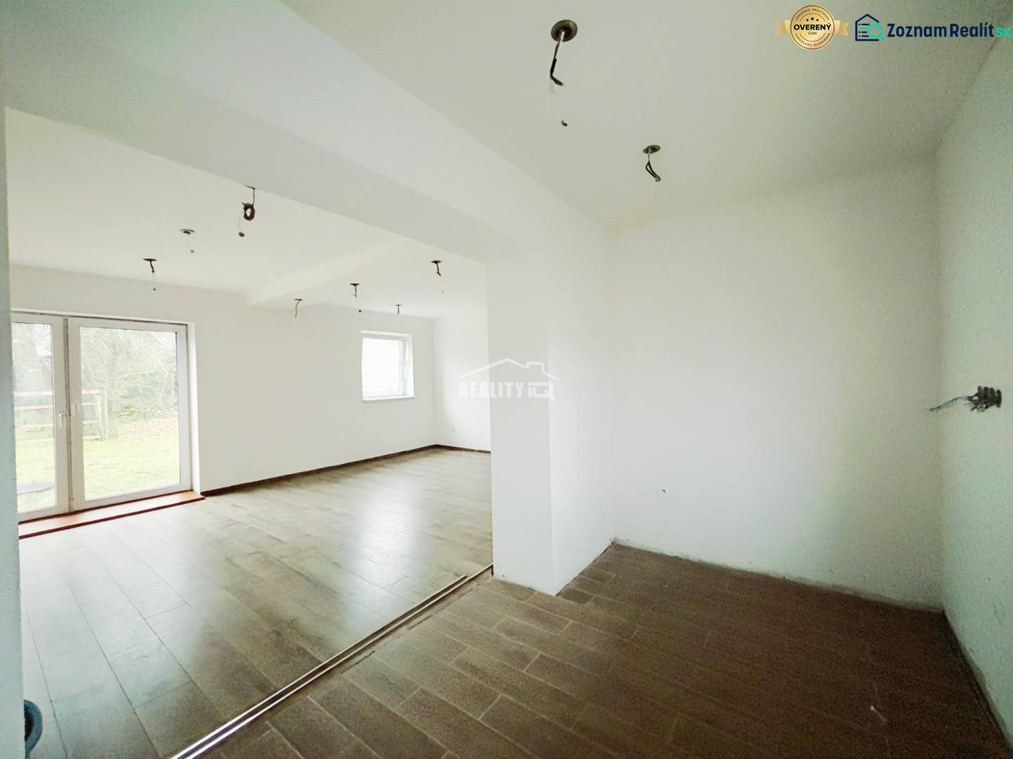 Innenraum eines Einfamilienhauses mit Holzboden und großen Fenstern zum Garten.