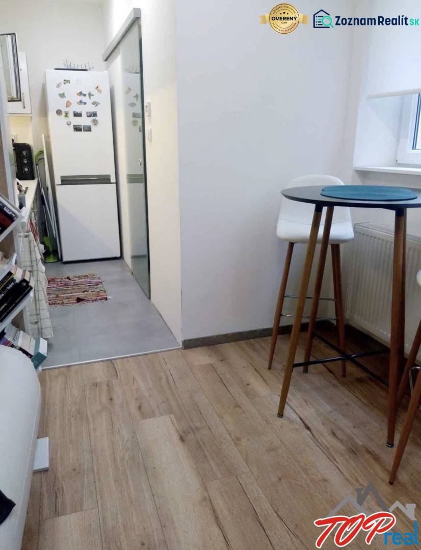 Küche in einer Einzimmerwohnung mit Holzboden, hoher Tisch und Stühle.