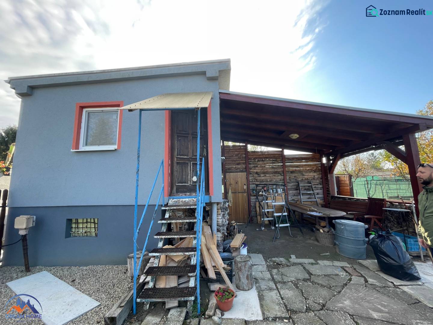 Ein Ferienhaus in Komárno in der Neuen Siedlung mit überdachter Terrasse und Holztreppe.
