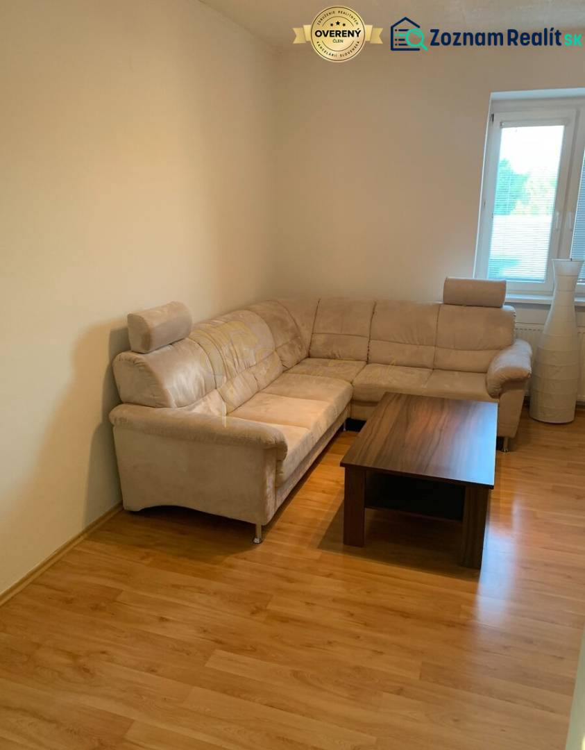 Wohnzimmer mit einem bequemen Sofa und einem Tisch auf einem Boden mit Holzdekor.