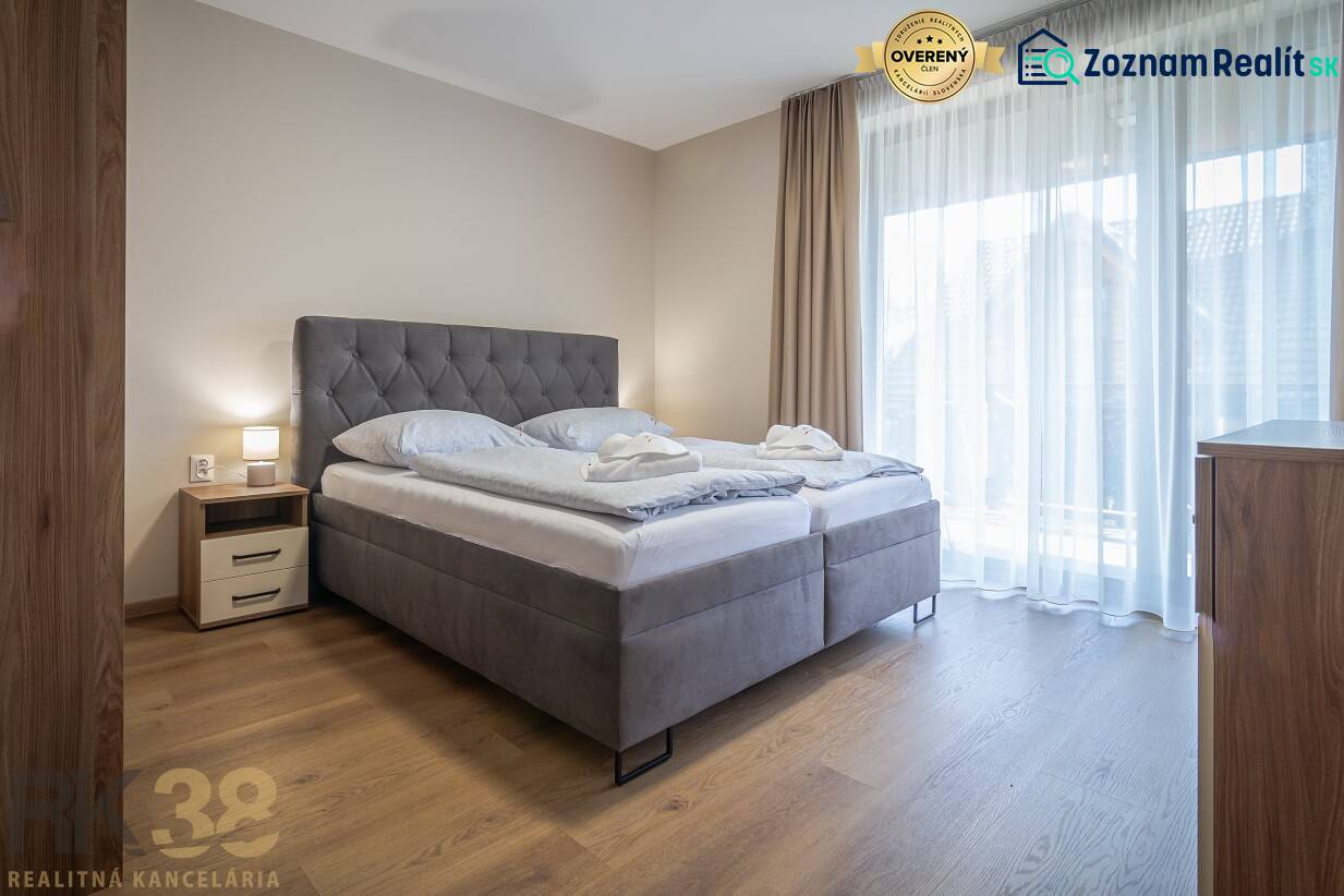 Schlafzimmer in einer 2-Zimmer-Wohnung mit einem großen Bett und einem Boden in Holzoptik.