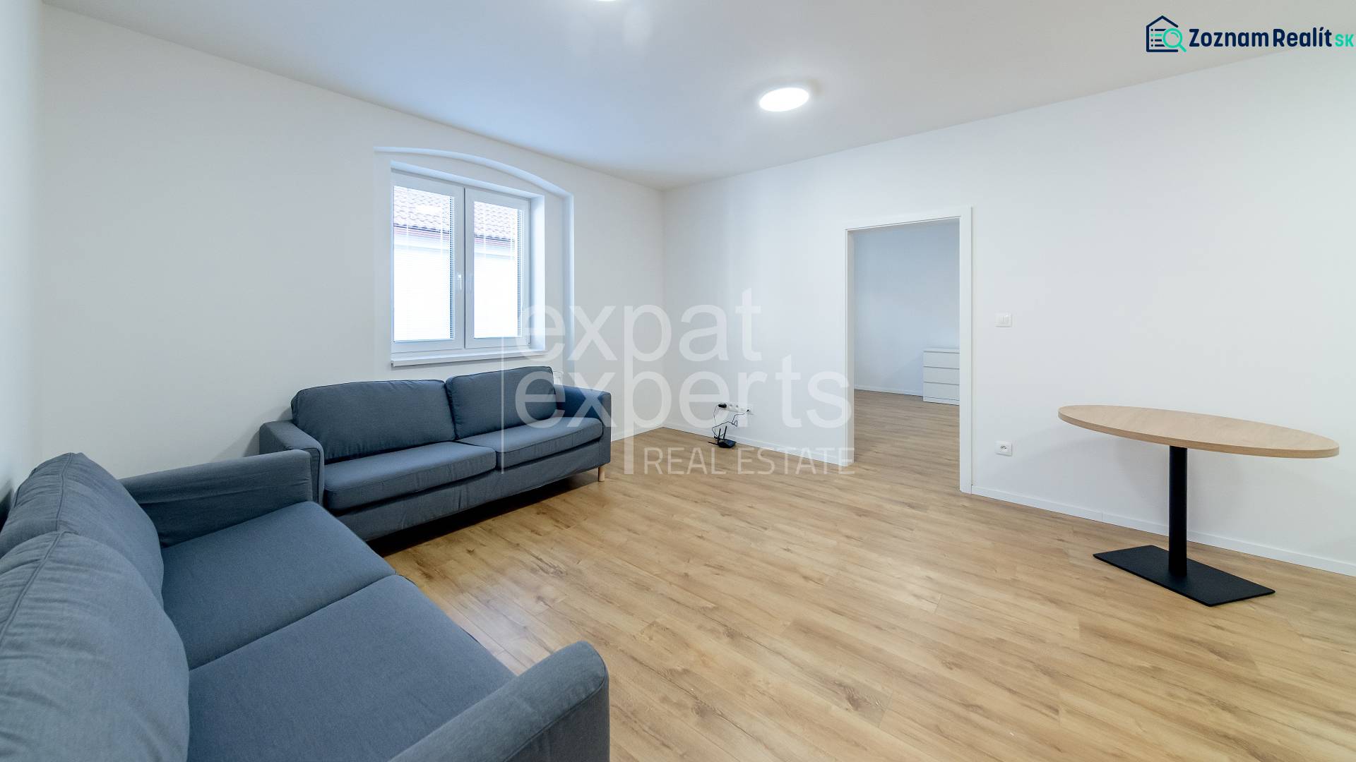 Wohnzimmer mit blauen Sofas und einem Tisch auf einem Boden mit Holzdekor.