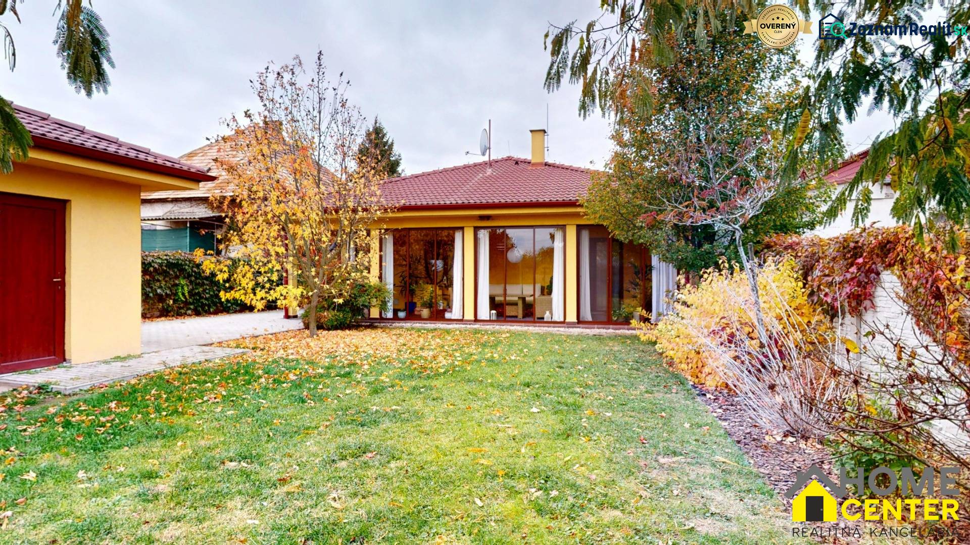 Ein Einfamilienhaus in der Ďatelinová-Straße in Iža mit Garten, Laubbäumen und Rasen.