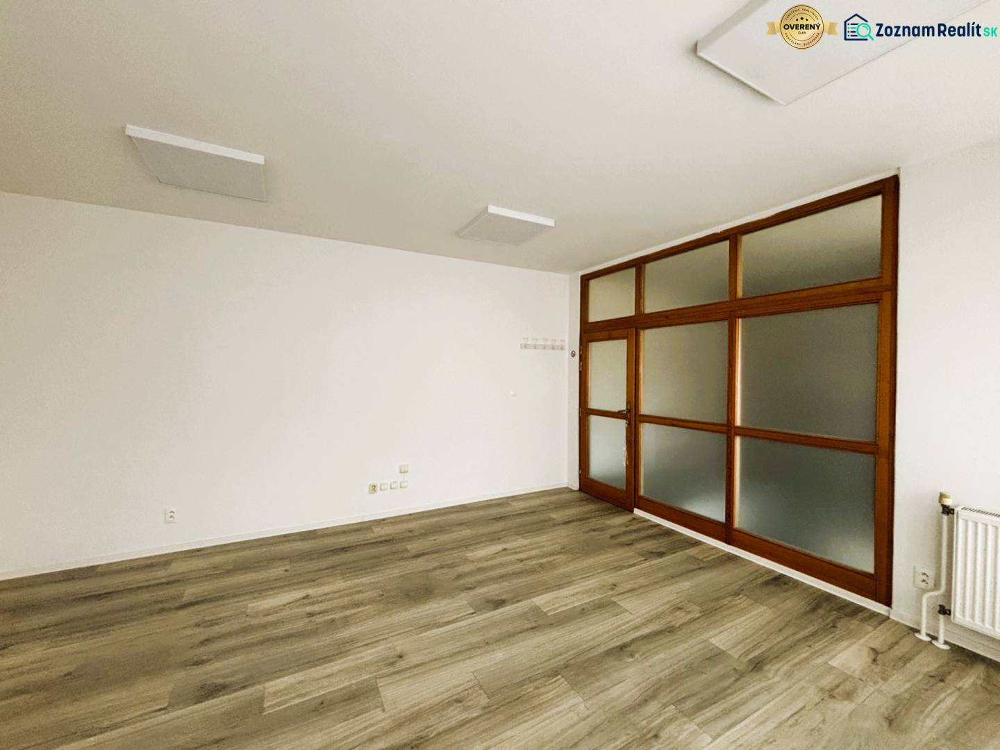 Geschäftsräume mit weißen Wänden und einem Boden in Holzoptik, Glastüren.