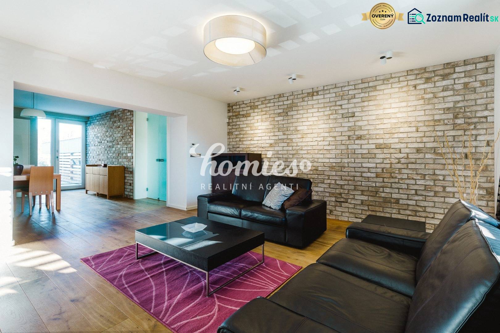 Wohnzimmer in einem Einfamilienhaus mit Ziegelwand und Boden in Holzoptik.