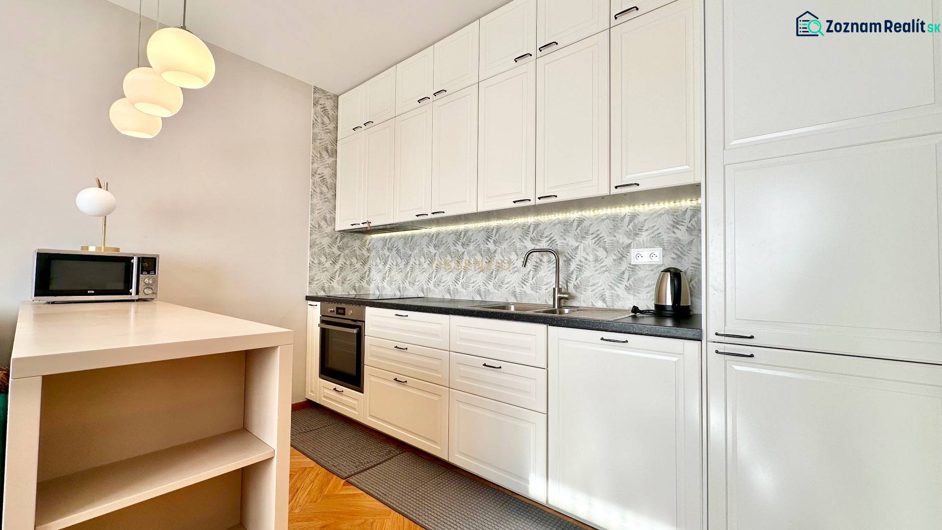 Küche in einer 3-Zimmer-Wohnung mit weißen Schränken und einem Boden in Holzoptik.