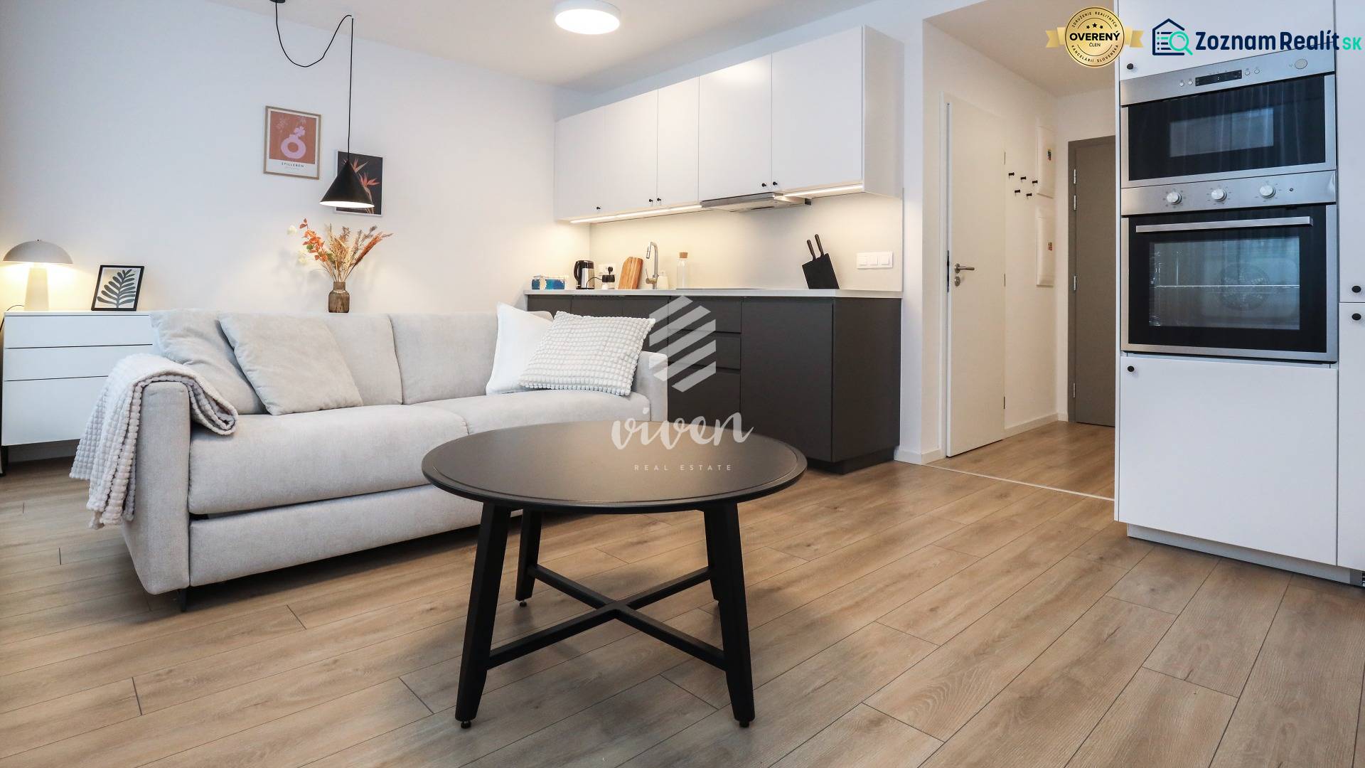 Wohnzimmer mit Küchenzeile in einer Einzimmerwohnung, Boden mit Holzdekor.