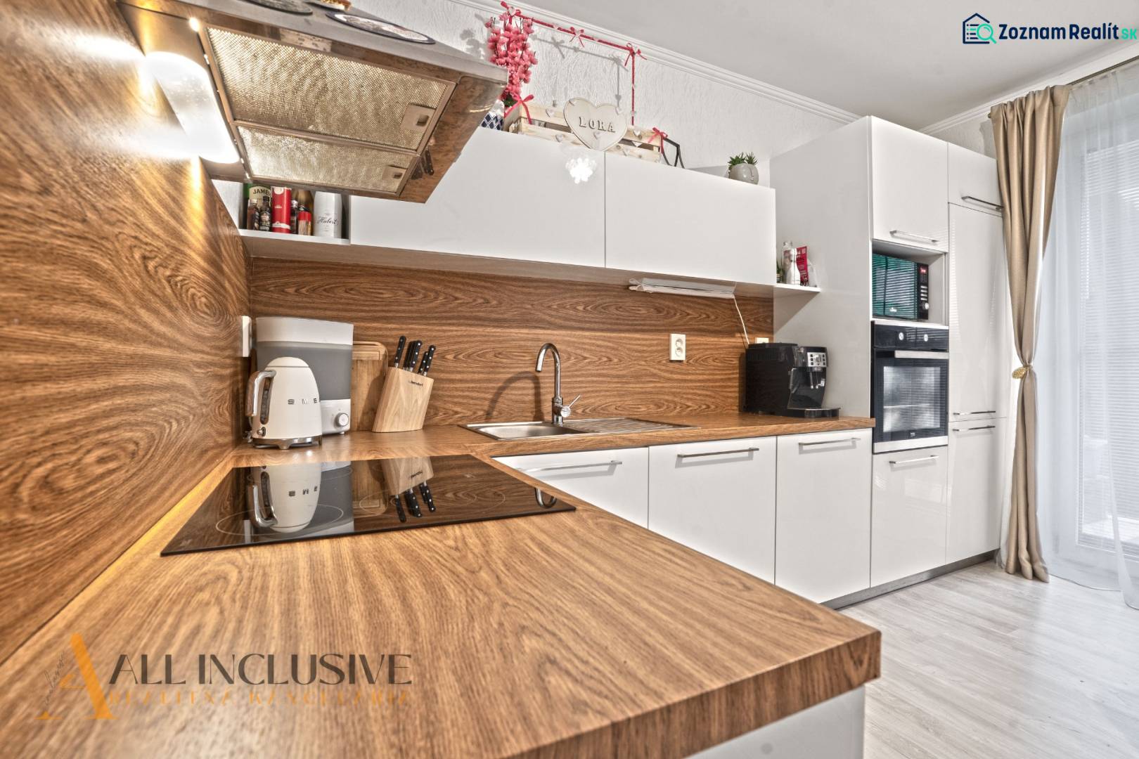 Küche in einer 3-Zimmer-Wohnung mit weißen Schränken und einem Boden in Holzoptik.