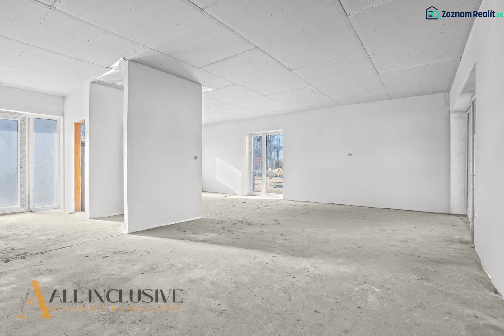 Ein leerer Innenraum in einem Einfamilienhaus mit weißen Wänden und großen Fenstern.