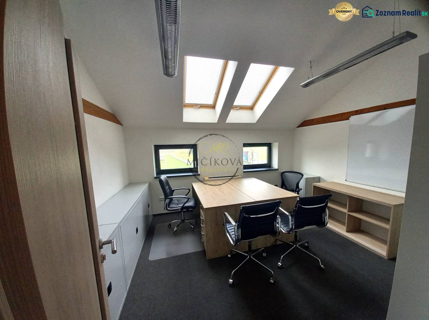 Ein Büro mit einem Boden in Holzoptik, Dachfenstern und Tischen mit Stühlen.