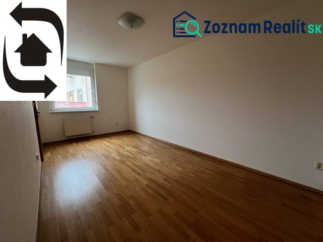 Ein leerer Raum in einer 3-Zimmer-Wohnung mit Holzboden und Fenster.