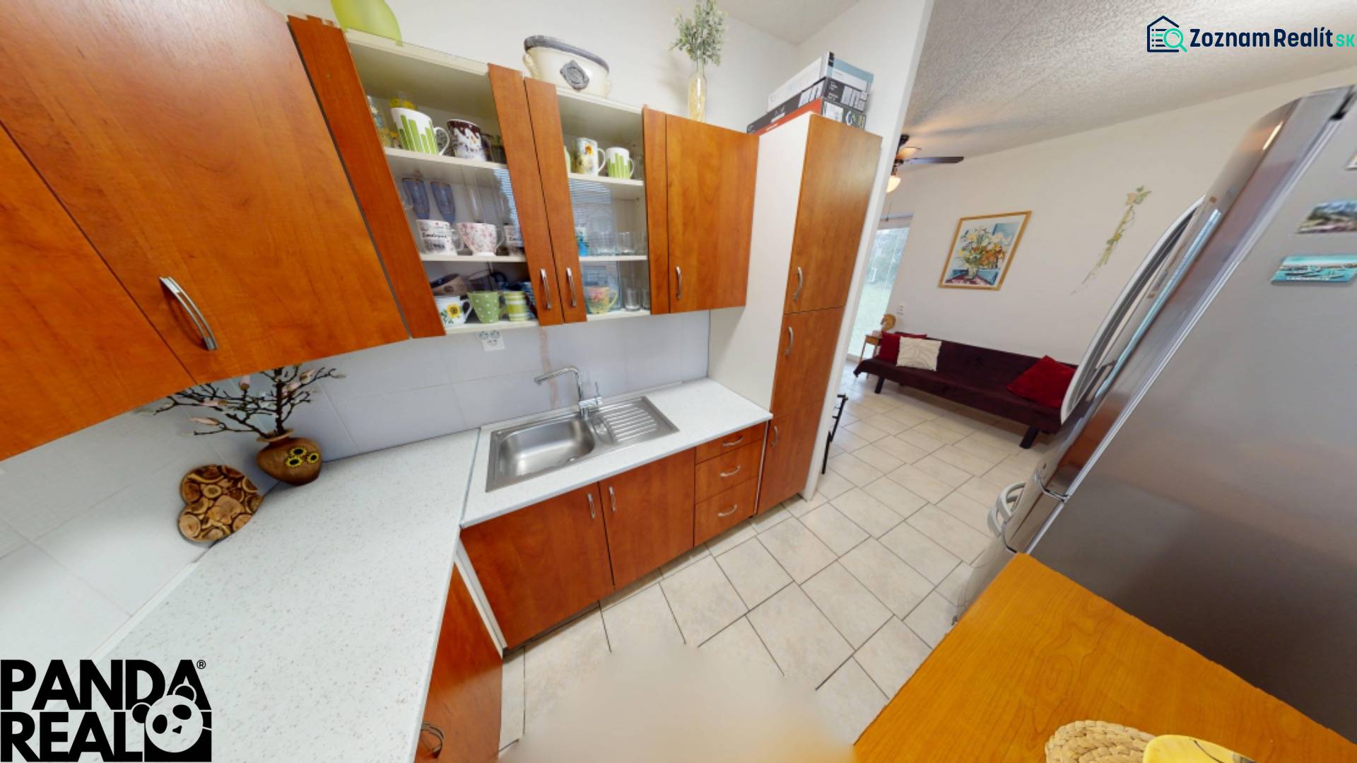 Küche in einer 3-Zimmer-Wohnung mit Holzdekor-Schränken, Kühlschrank und Essecke.