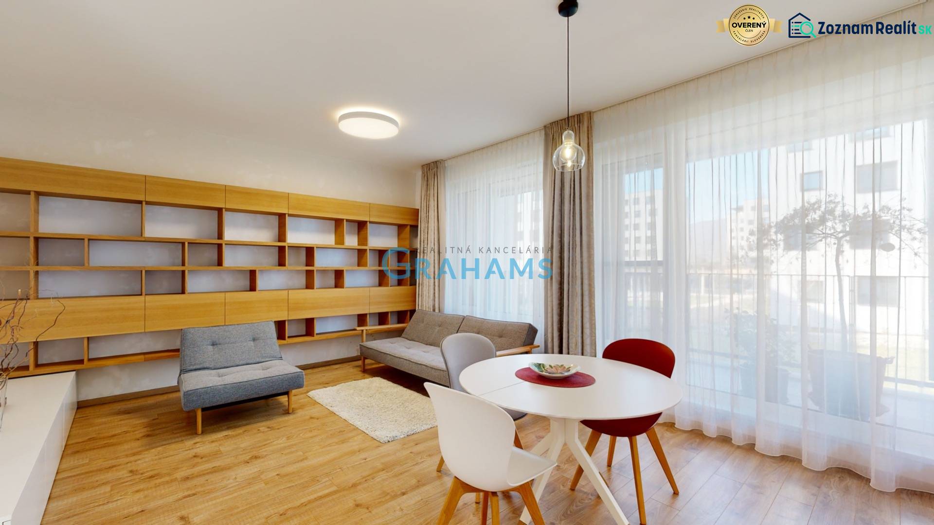 Helles Wohnzimmer mit Sitzbereich, Bibliothek und Holzboden in einer Vierzimmerwohnung.