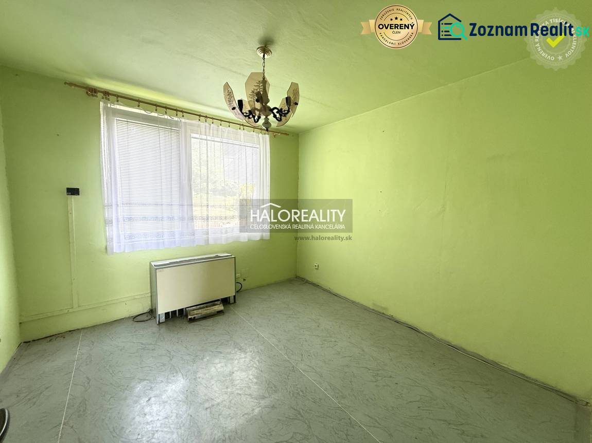 Ein Zimmer mit einem Kronleuchter, einem Fenster und einem Heizkörper in einer 3-Zimmer-Wohnung.