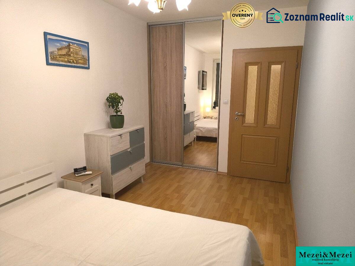 Schlafzimmer in einer 2-Zimmer-Wohnung mit Holzboden, Schränken mit Spiegel und Bild.