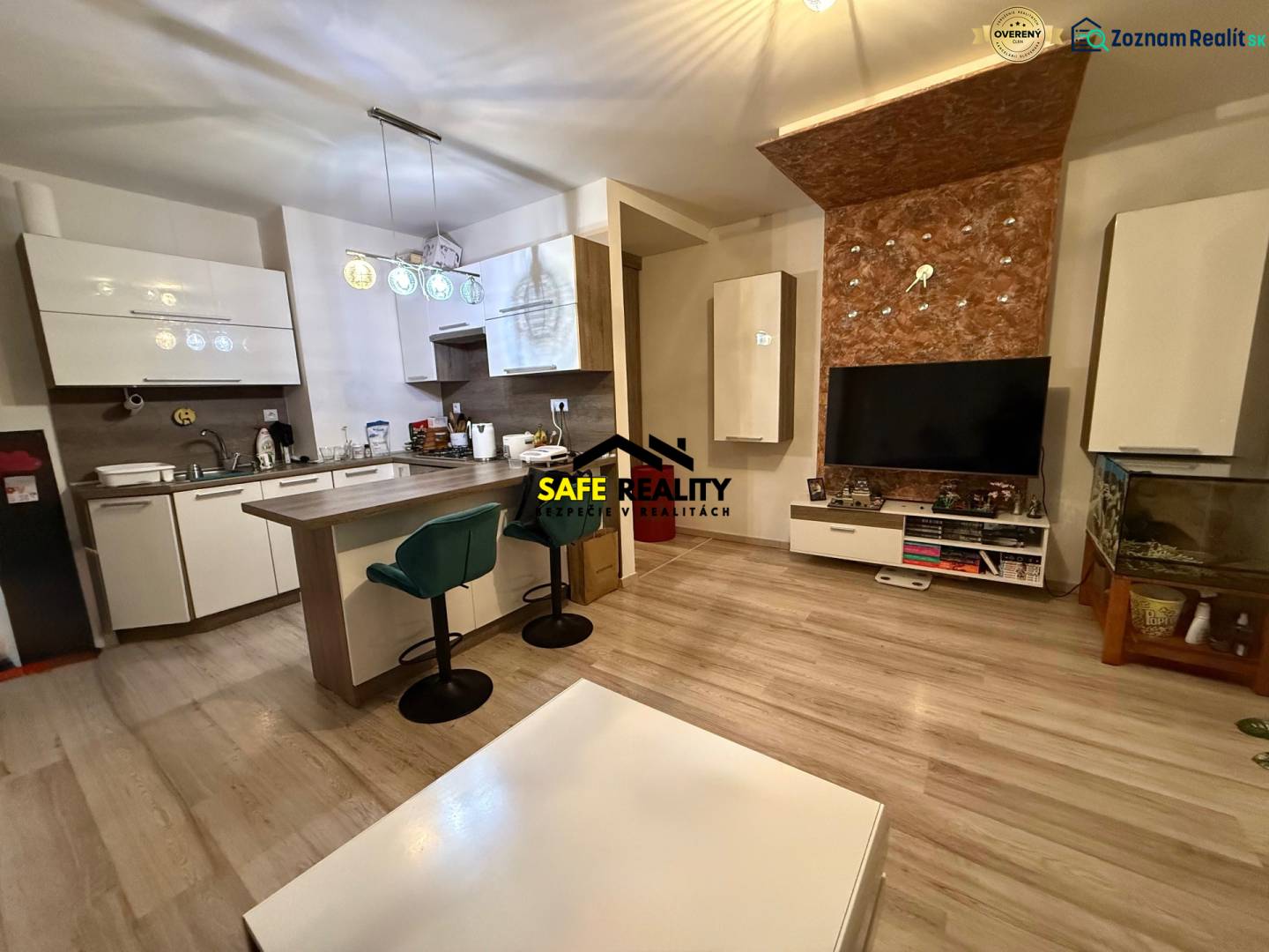 Wohnzimmer mit Küche, Bartresen und Holzboden in einer Zweizimmerwohnung.