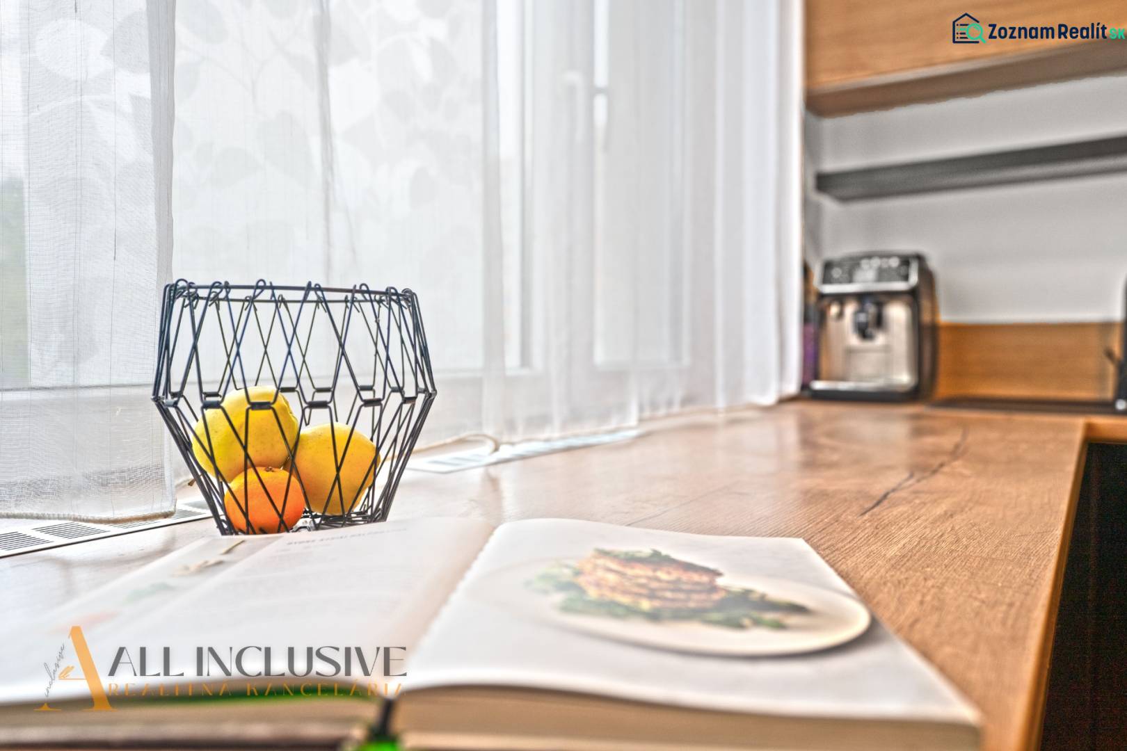 Offene Küche in einer 3-Zimmer-Wohnung mit Holzdekor, Obstschale auf dem Tisch.