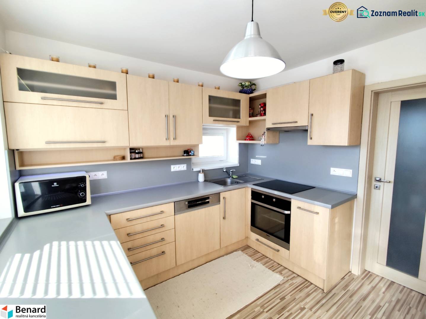 Küche in einem Einfamilienhaus mit Holzdekor und grauer Arbeitsplatte.