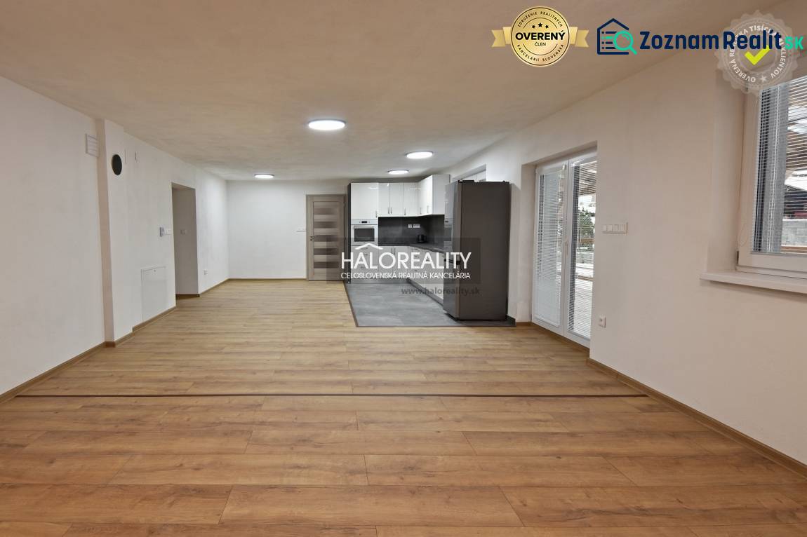 Wohnzimmer in einem Einfamilienhaus mit Küche, Holzboden, weiße Wände.