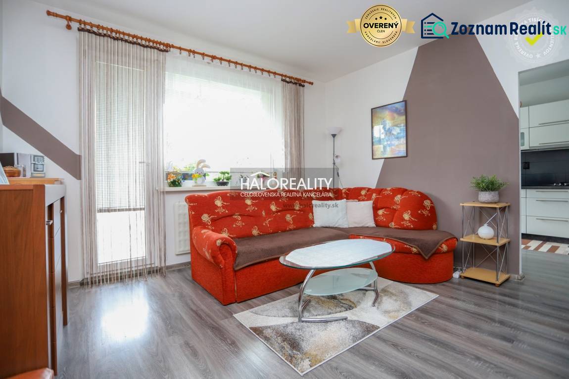 Wohnzimmer in einer 3-Zimmer-Wohnung mit einem orangefarbenen Sofa und einem Boden in Holzoptik.